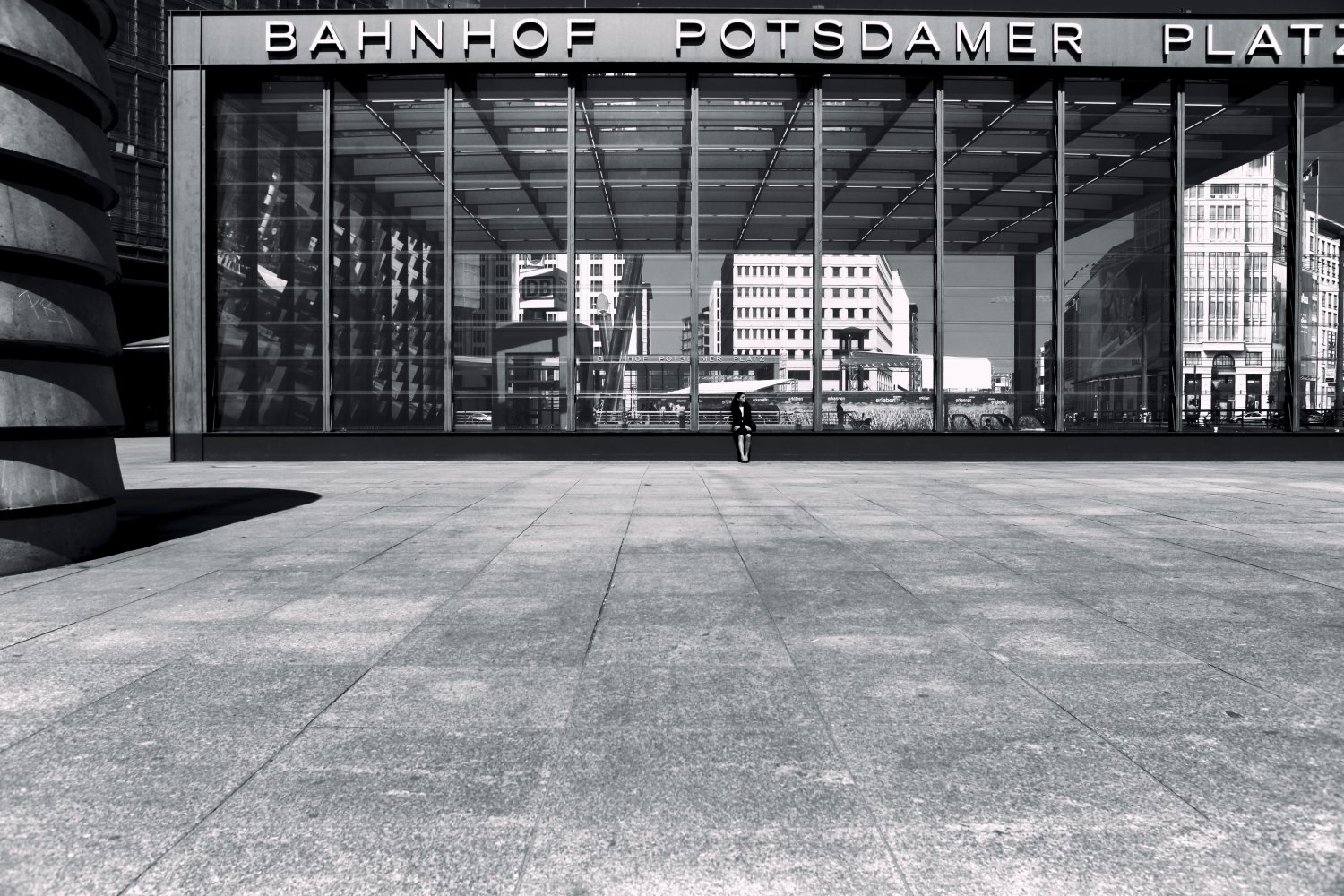 Bahnhof Potsdamer Platz in Berlin: Minimalistisches Schwarzweiß-Foto mit moderner Architektur und einzelner Person