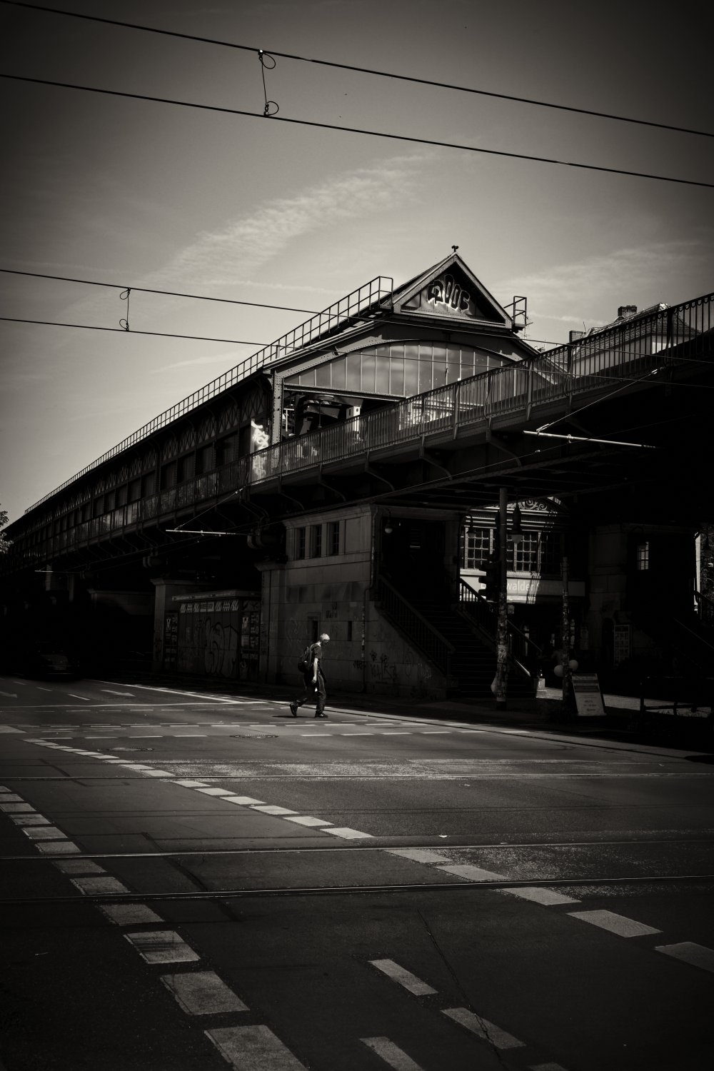Schwarzweiß-Fotografie der Eberswalder Straße in Berlin mit historischer Eisenbahnbrücke und Bahnhof