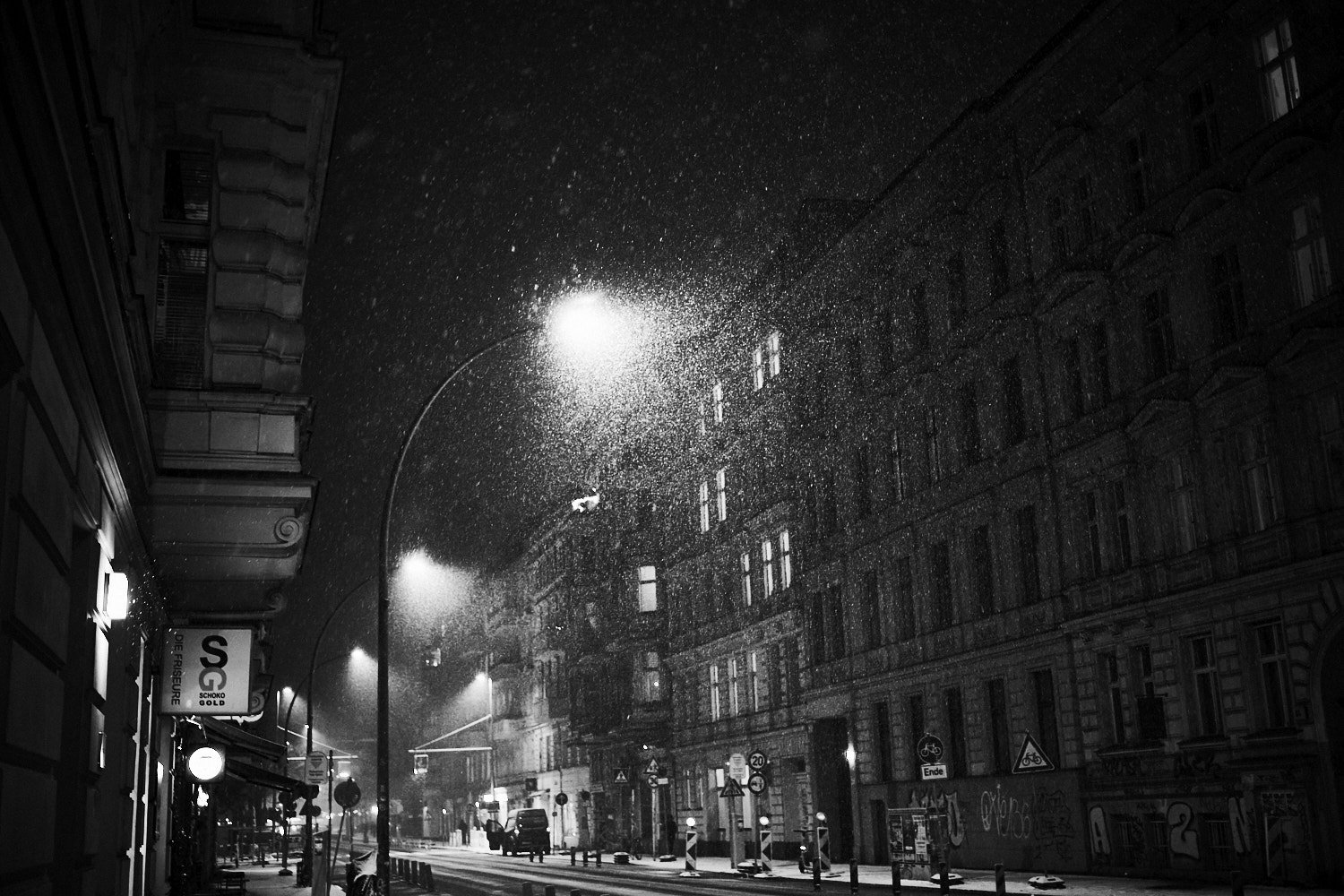 Verschneite Straße in Schöneberg bei Nacht mit Straßenlaternen und historischen Gebäuden
