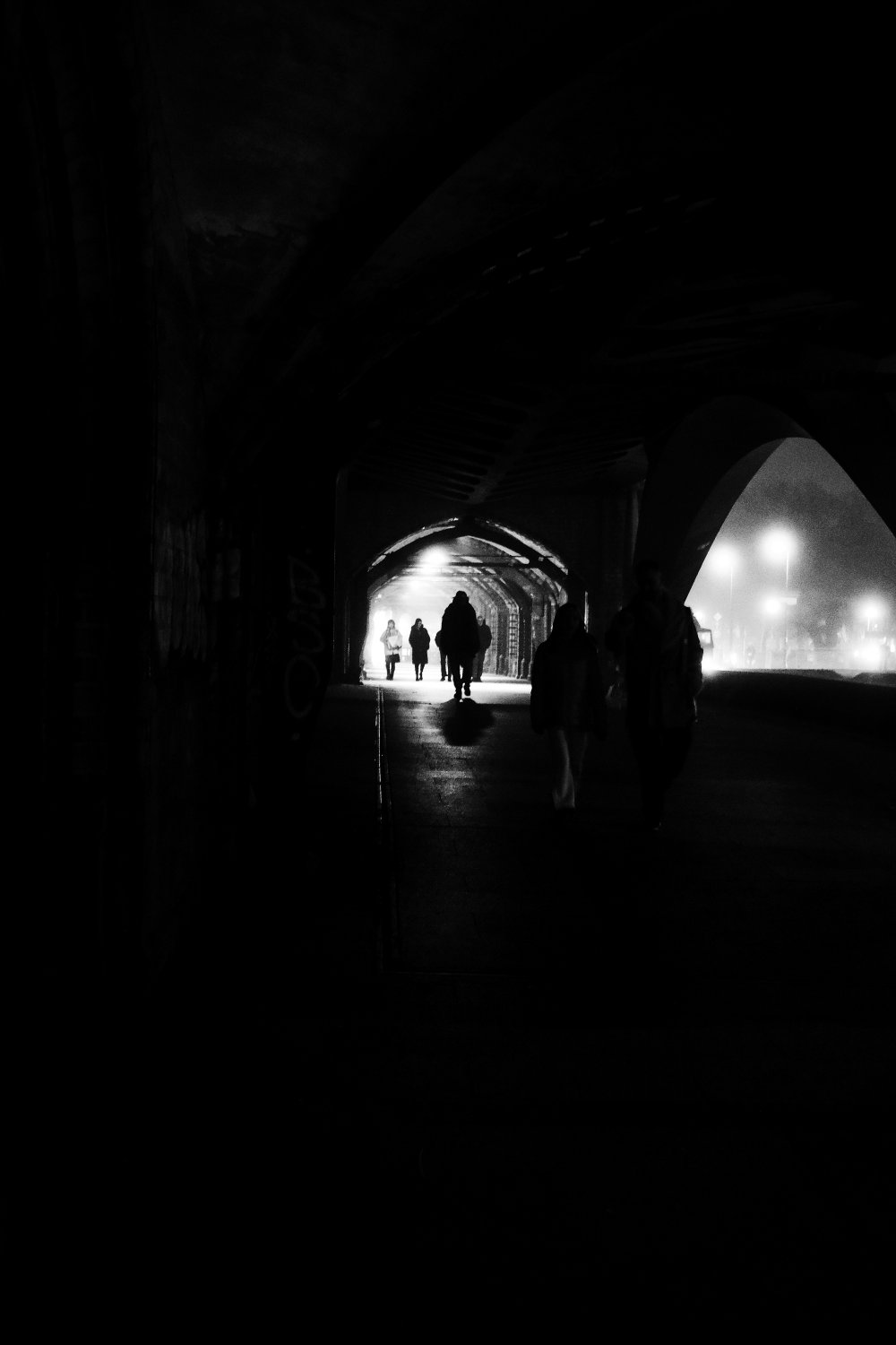 Schwarzweiß-Fotografie der Oberbaumbrücke Berlin mit Silhouetten von Menschen im Tunnel