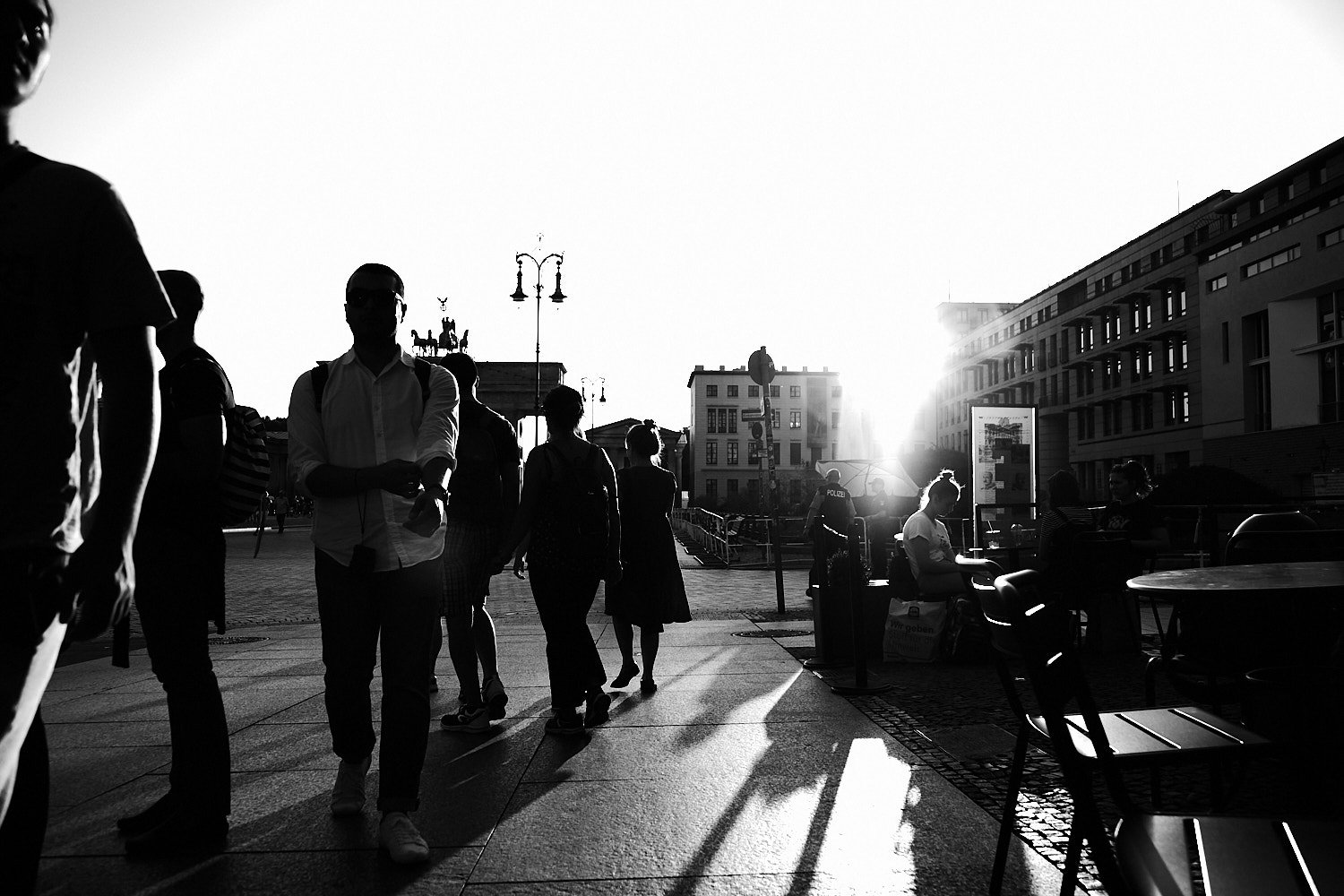 Schwarzweiß-Straßenszene am Pariser Platz in Berlin mit Fußgängern und historischen Gebäuden bei Gegenlicht