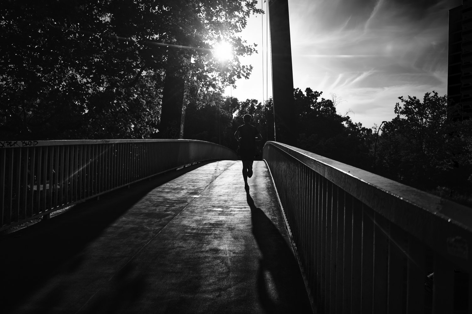 Läufer auf der Volksparksteg-Brücke in Schöneberg, Schwarz-Weiß-Fotografie mit Gegenlicht